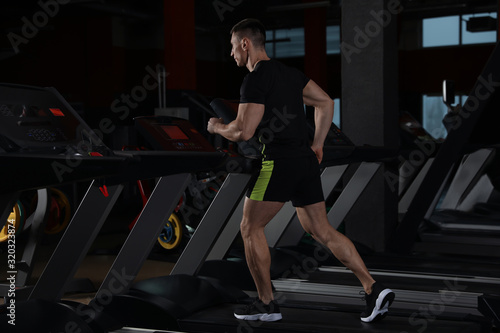 Man working out on treadmill in modern gym © New Africa