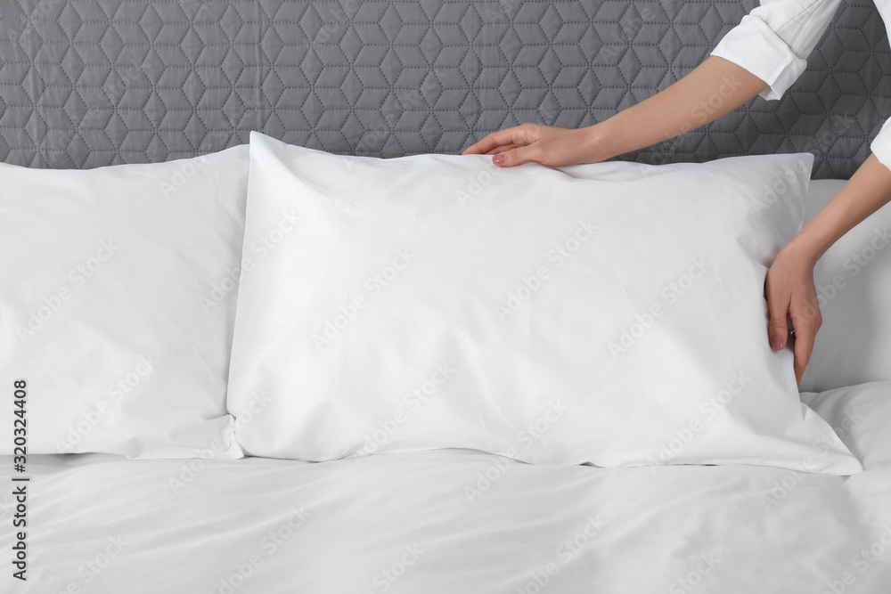 Woman fluffing soft pillow in bedroom, closeup Woman fluffing soft pillow in bedroom, closeup