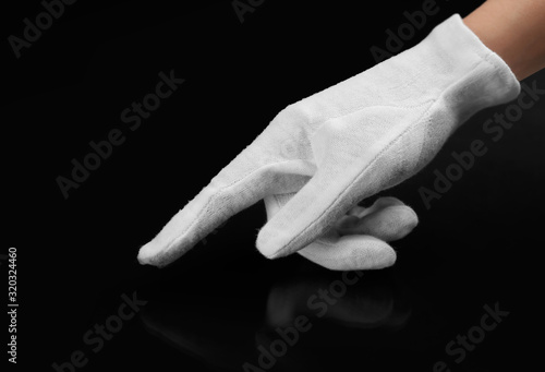 Person in white glove checking cleanliness of black background, closeup photo