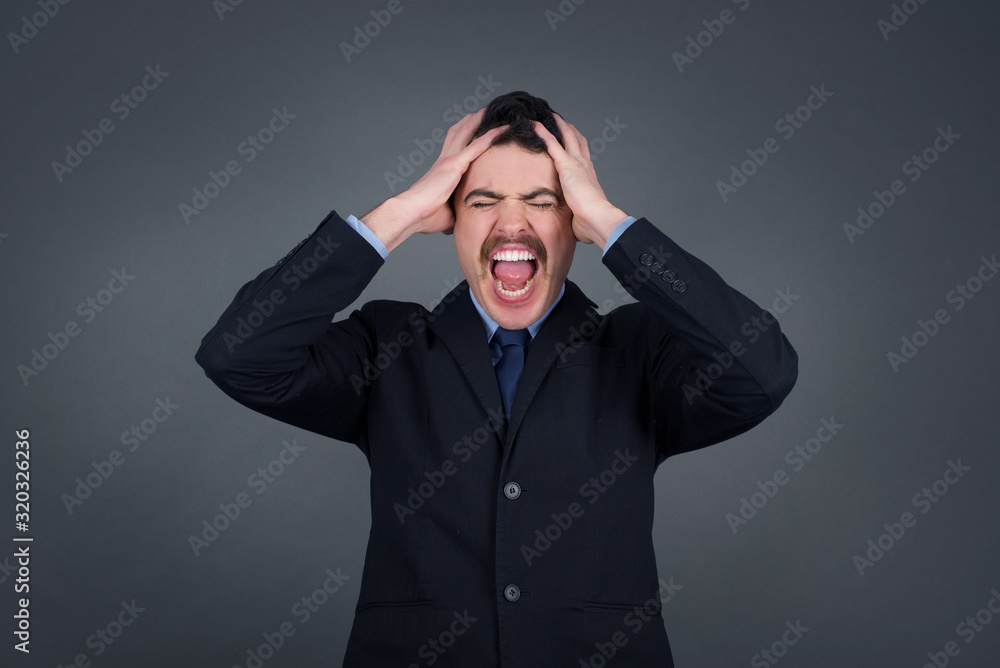 Shocked panic Caucasian man dressed in stylish clothing holding hands on head and screaming in despair and frustration while being late for plane, his eyes full of terror, mouth dropped open Shocked panic Caucasian man dressed in stylish clothing holding hands on head and screaming in despair and frustration while being late for plane, his eyes full of terror, mouth dropped open