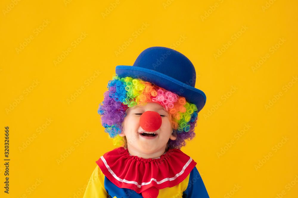 Funny kid clown playing against yellow background Funny kid clown playing against yellow background