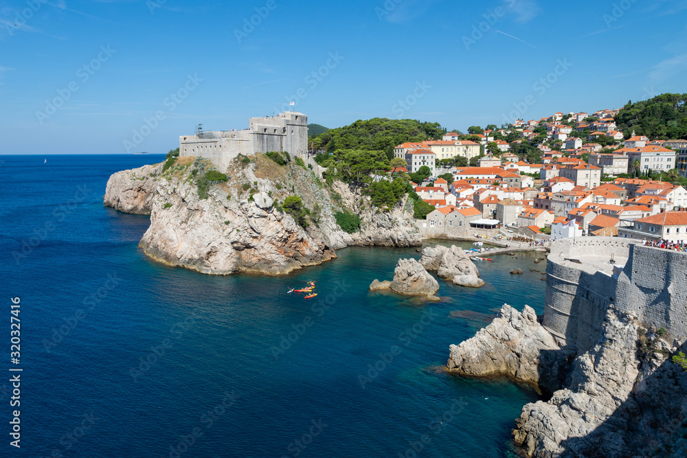 Fort Lovrijenac and Pile Harbour in Dubrovnik, Croatia. A view from above looking towards a rocky harbour and a fort positioned on a rocky outcrop surrounded  by the Adriatic sea.
