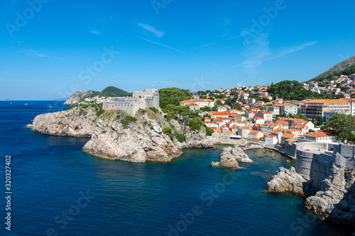 Fort Lovrijenac and Pile Harbour in Dubrovnik, Croatia. A view from above looking towards a rocky harbour and a fort positioned on a rocky outcrop surrounded by the Adriatic sea.