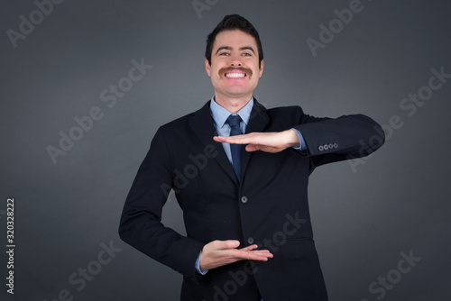 Young handsome businessman wearing casual clothes over isolated background gesturing with hands showing big and large size sign, measure symbol. Smiling looking at the camera. Measuring concept.