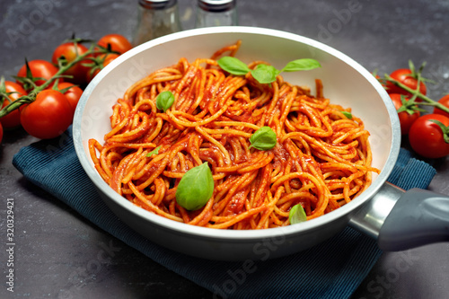 Close up of spaghetti with tomato suace in a pan on black background