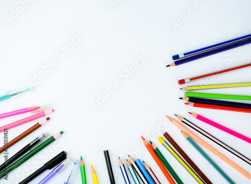 Writing materials randomly scattered on a white background,which includes pens and pencils