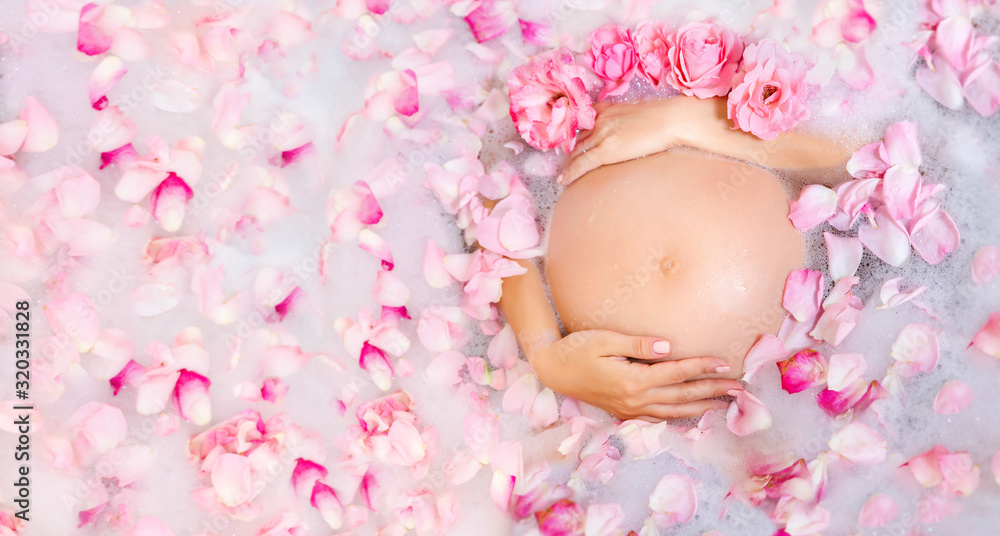 Beautiful pregnant young woman caring her belly in bubble bath with ...