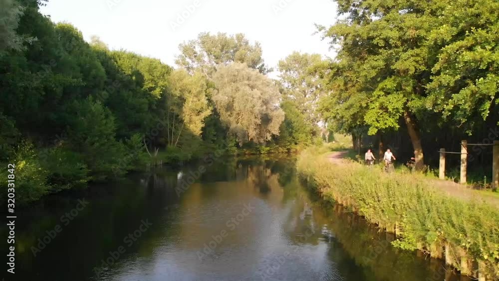 Aerial view of a canal in belgium in the afternoon during summer with people cycling, birdview