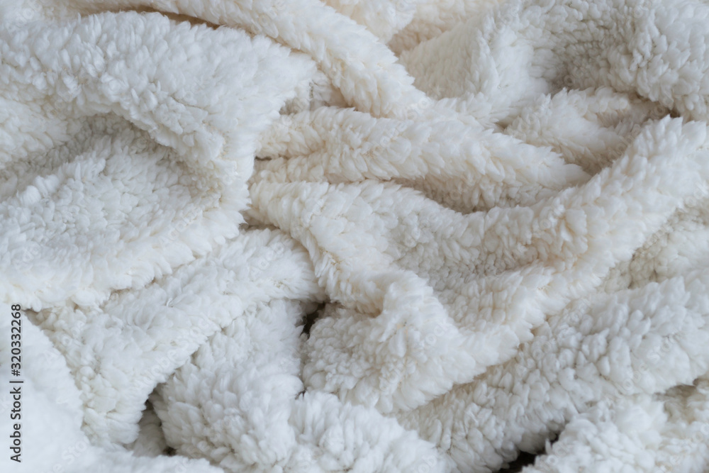 Texture of a soft plaid. Crumpled white warm blanket. Fabric crumpled in folds for background or wallpaper. Texture of a soft plaid. Crumpled white warm blanket. Fabric crumpled in folds for background or wallpaper.