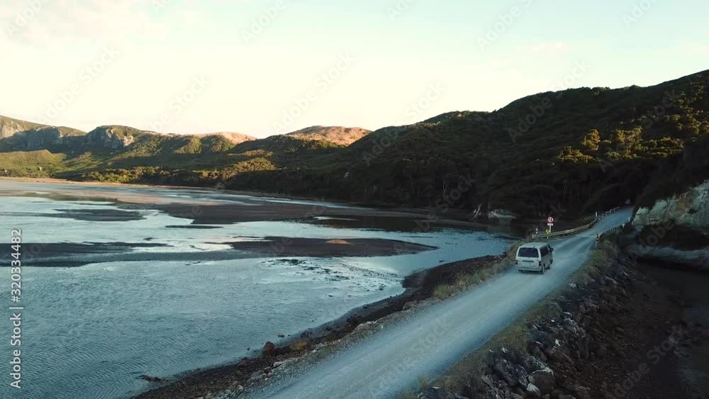 Van Moving on Countryside Road Between Lagoons in Puponga Area, New Zealand. Aerial View Van Moving on Countryside Road Between Lagoons in Puponga Area, New Zealand. Aerial View