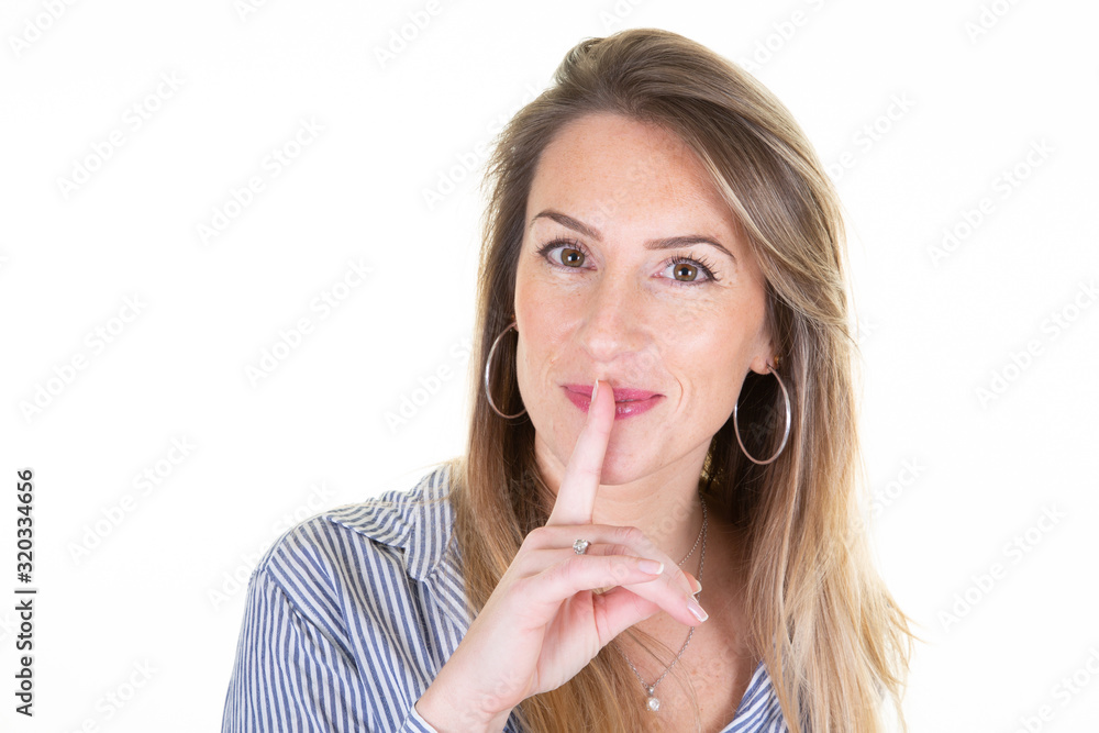 Portrait of woman holding index finger on lips quiet gesture silence sign on white background Portrait of woman holding index finger on lips quiet gesture silence sign on white background