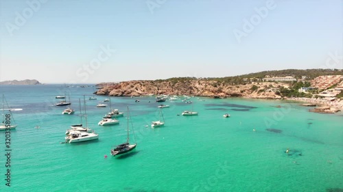 amazng drone footage paning right from cala tarida paradise beach in ibiza with boats yachts and people at teh beach and in the water photo