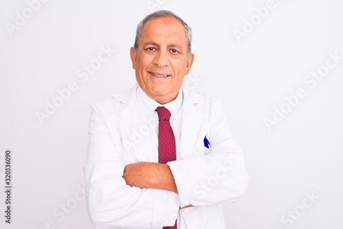 Senior grey-haired scientist man wearing coat standing over isolated white background happy face smiling with crossed arms looking at the camera. Positive person. © Krakenimages.com