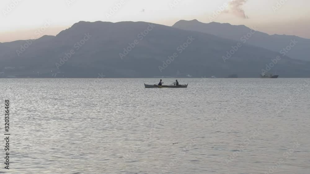 Fishermen paddling a boat with mountains in the background, Subic, Philippines Fishermen paddling a boat with mountains in the background, Subic, Philippines