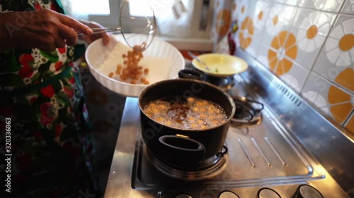 Drain boiling oil from fried struffoli pastries to put in bowl