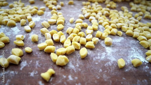 Close up panning of floured struffoli on wooden board. Slow motion