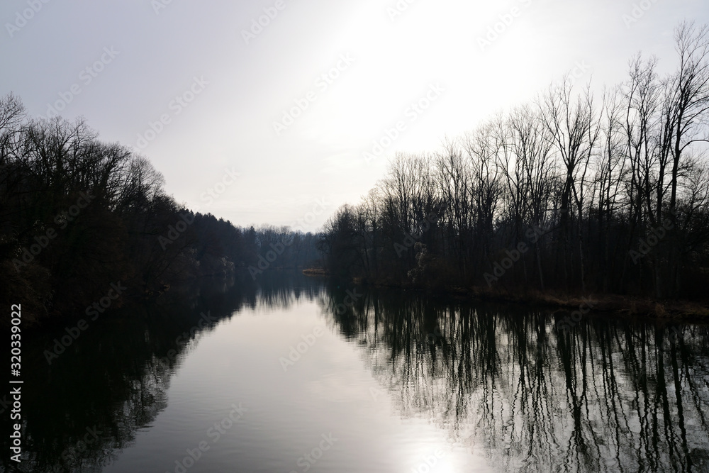 Fluss mit gespiegelter Baumsilhouette