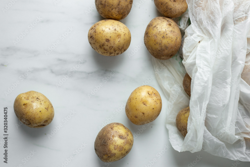 Fototapeta premium fresh bio organic potatoes in recyclable bag on white marble background with copy space