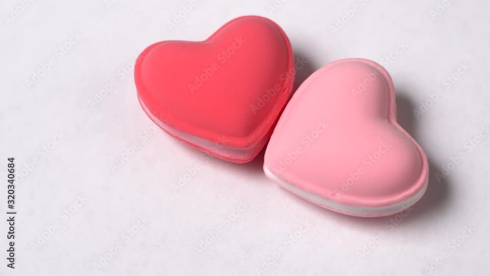 Two heart-shaped macaroons rotate on a white background. Valentine's day concept. Two heart-shaped macaroons rotate on a white background. Valentine's day concept.