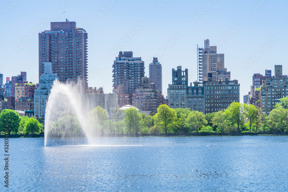 Many fresh green trees and plants grow along the Central Park Reservoir toward to the Central Park East residents in the morning at Central Park at New York City NY USA on May. 06 2019. Many fresh green trees and plants grow along the Central Park Reservoir toward to the Central Park East residents in the morning at Central Park at New York City NY USA on May. 06 2019.