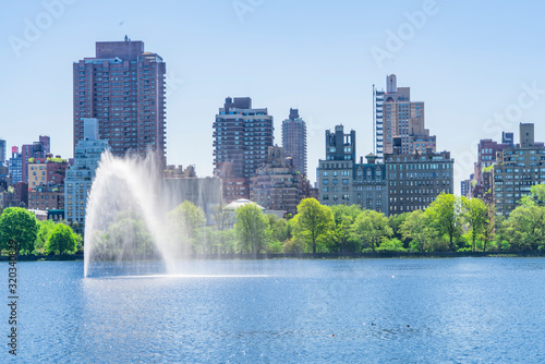 Many fresh green trees and plants grow along the Central Park Reservoir toward to the Central Park East residents in the morning at Central Park at New York City NY USA on May. 06 2019.