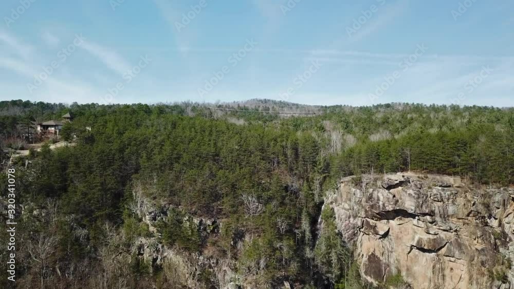 Slow motion drone shot of trees and sky next to a cliff Slow motion drone shot of trees and sky next to a cliff