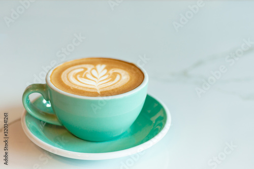 Fresh latte coffee in green cup on marble table with copy space.