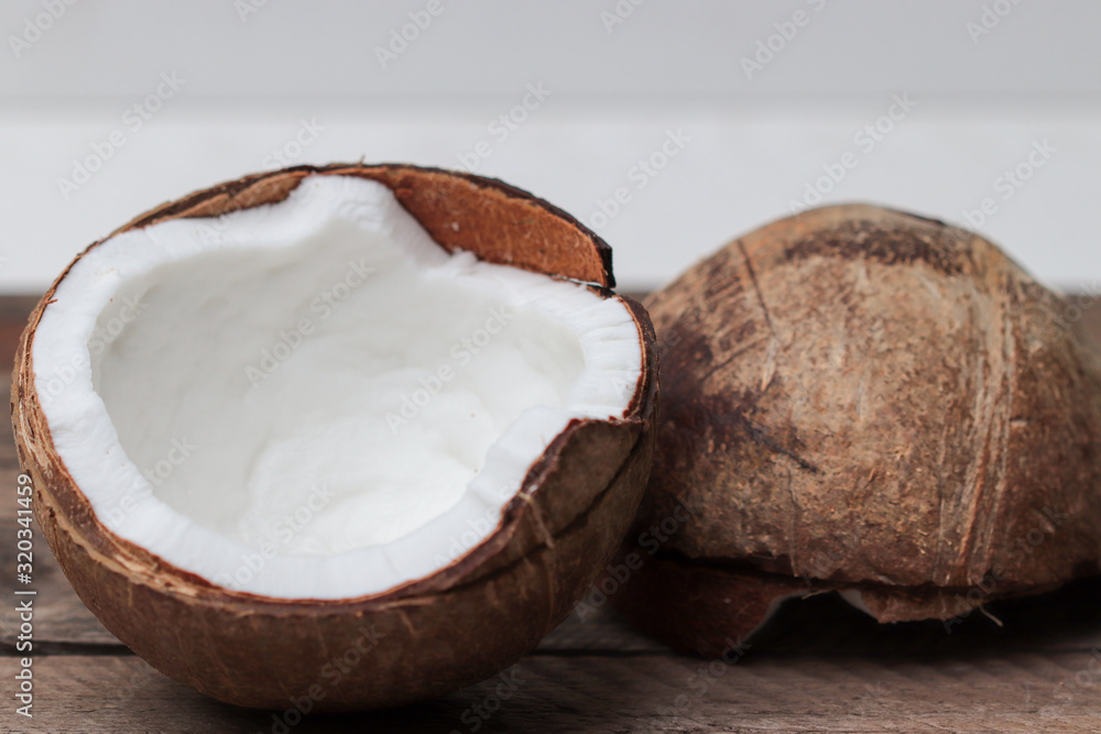 two halves of a coconut on a wooden table two halves of a coconut on a wooden table