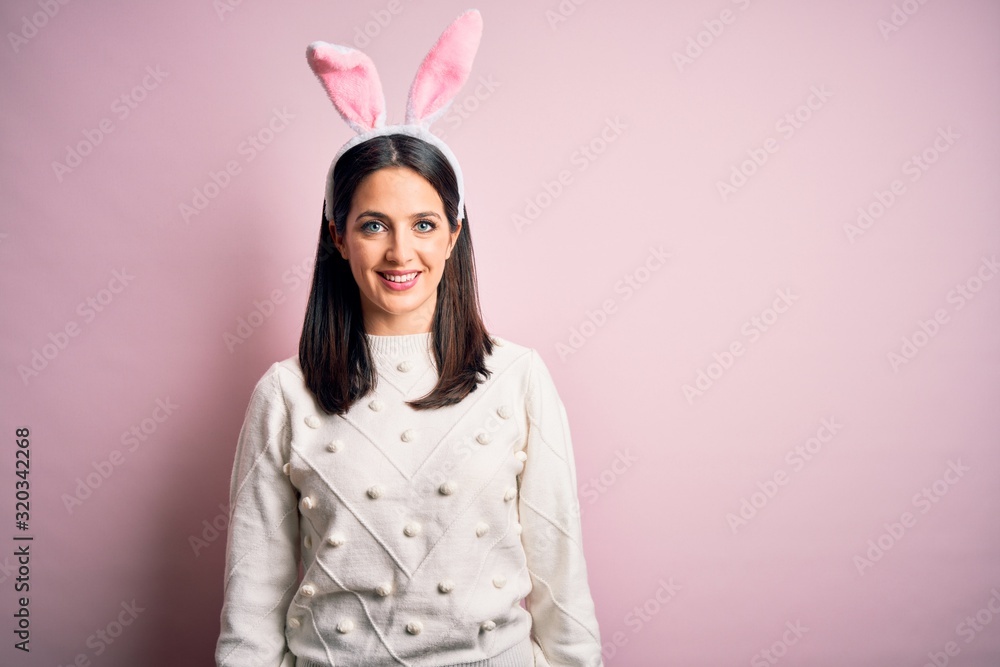 Young caucasian woman wearing cute easter rabbit ears over pink isolated background with a happy and cool smile on face. Lucky person.
