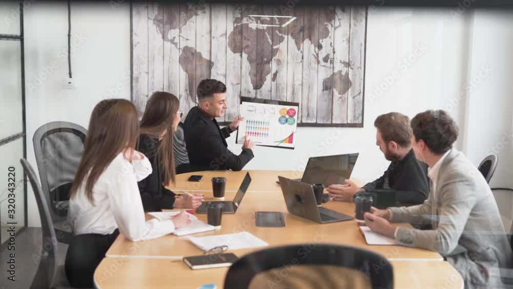 business team develops strategy sitting in the office by the glass, the manager shakes up the graphs business team develops strategy sitting in the office by the glass, the manager shakes up the graphs