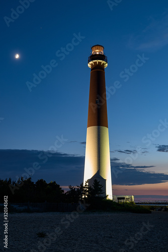 The Barnegat lightouse in New Jersey in early evening with a moonrise and stars