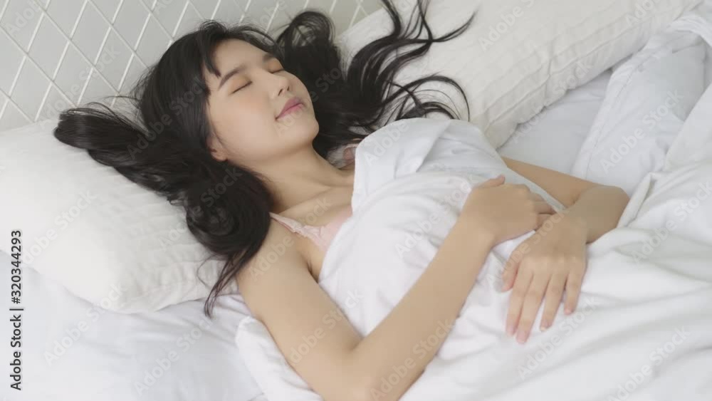 Beautiful asian young woman sleeping lying in bed with head on pillow comfortable and happy in the bedroom moving panning camera, girl with relax and leisure for health, lifestyle concept. Beautiful asian young woman sleeping lying in bed with head on pillow comfortable and happy in the bedroom moving panning camera, girl with relax and leisure for health, lifestyle concept.