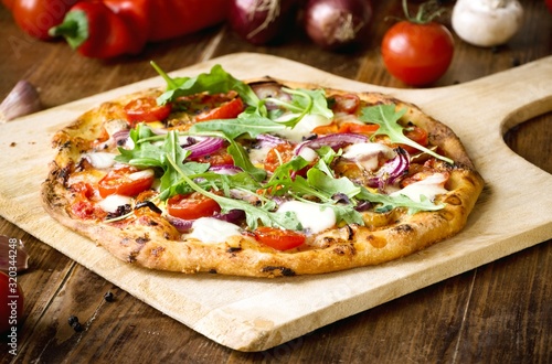 Obraz na plátně Freshly baked pizza with arugula, tomato, red onion and mozzarella