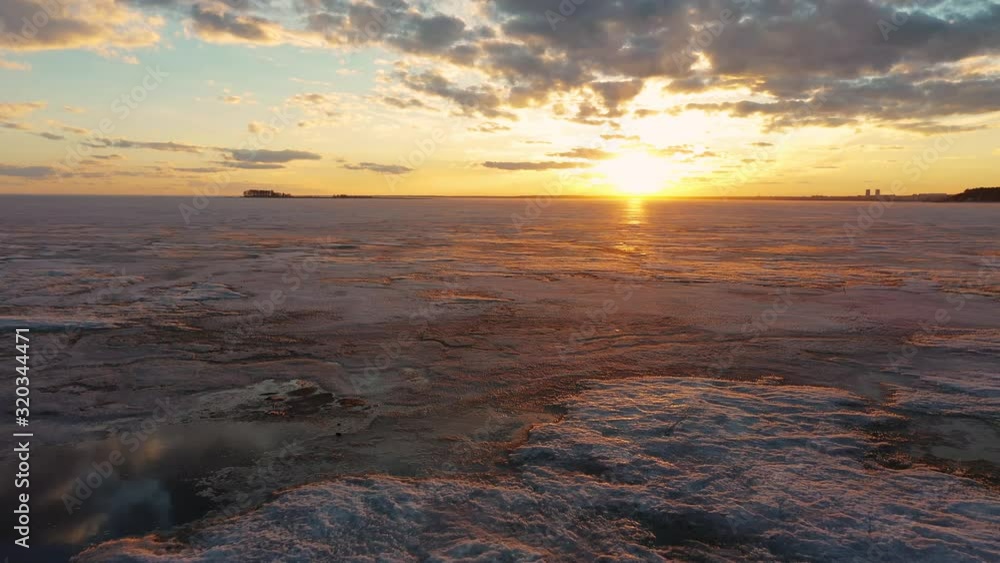 Flying over frozen sea at amazing sunset with red Sun and clouds Flying over frozen sea at amazing sunset with red Sun and clouds