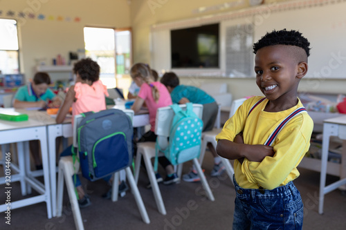 Schoolboy standing with arms crossed in an elementary school classroom