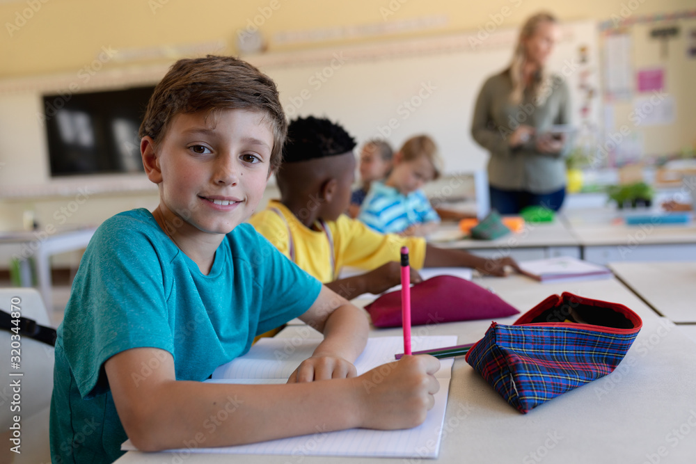 Fototapeta premium Schoolboy sitting at a desk in an elementary school classroom