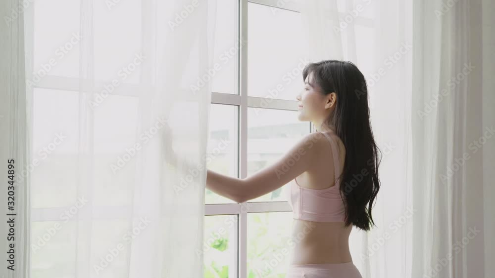 Beautiful young asian woman wake up and walking to window with open curtain in the morning with cosy, sexy girl in underwear smiling relax and resting in the vacation with happy, lifestyle concept. Beautiful young asian woman wake up and walking to window with open curtain in the morning with cosy, sexy girl in underwear smiling relax and resting in the vacation with happy, lifestyle concept.
