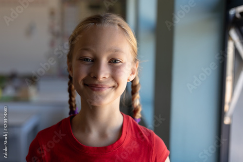 Schoolgirl with blonde hair in plaits looking to camera in an elementary school classroom