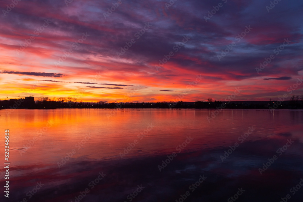 the majestic sunset over the lake. colorful saturated clouds reflected in water. dramatic scene. beautiful landscape. color in nature. beauty in the world