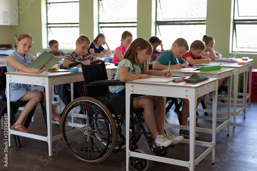 Group of schoolchildren sitting at desks in an elementary school classroom