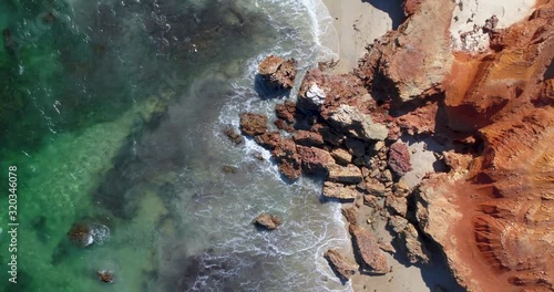 waves crashing agains red rock on the beach photo