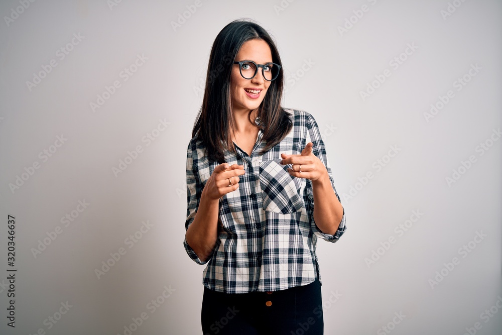 Young brunette woman with blue eyes wearing casual shirt and glasses over white background pointing fingers to camera with happy and funny face. Good energy and vibes. Young brunette woman with blue eyes wearing casual shirt and glasses over white background pointing fingers to camera with happy and funny face. Good energy and vibes.