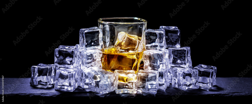 Whiskey on the rocks, whiskey glass, ice cubes on a slate board Whiskey on the rocks, whiskey glass, ice cubes on a slate board