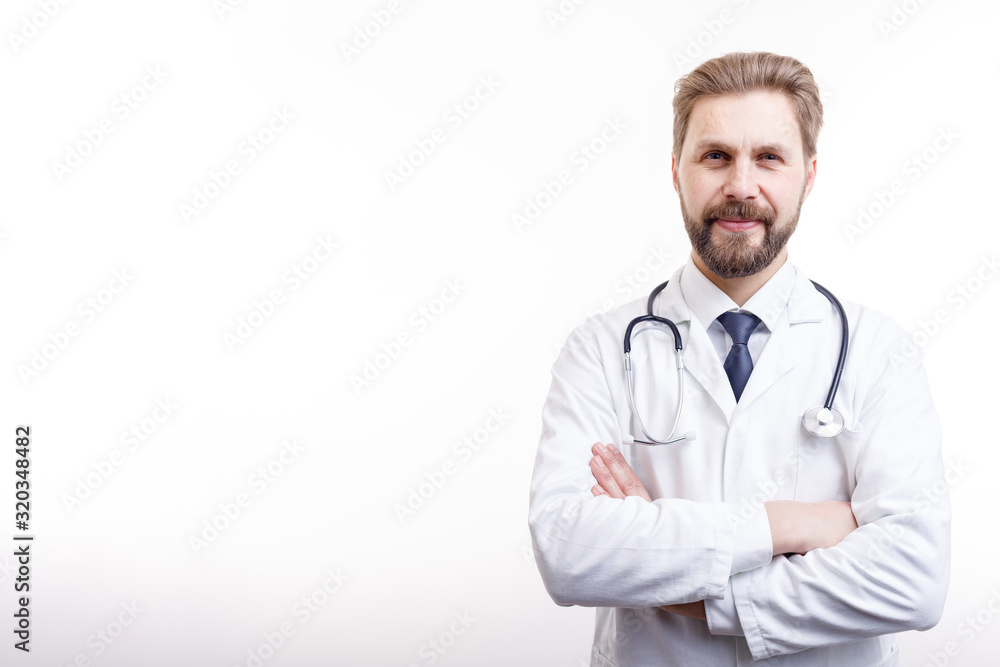 Smiling bearded doctor in white coat with stethoscope posing arms crossed isolated white background copyspace Smiling bearded doctor in white coat with stethoscope posing arms crossed isolated white background copyspace