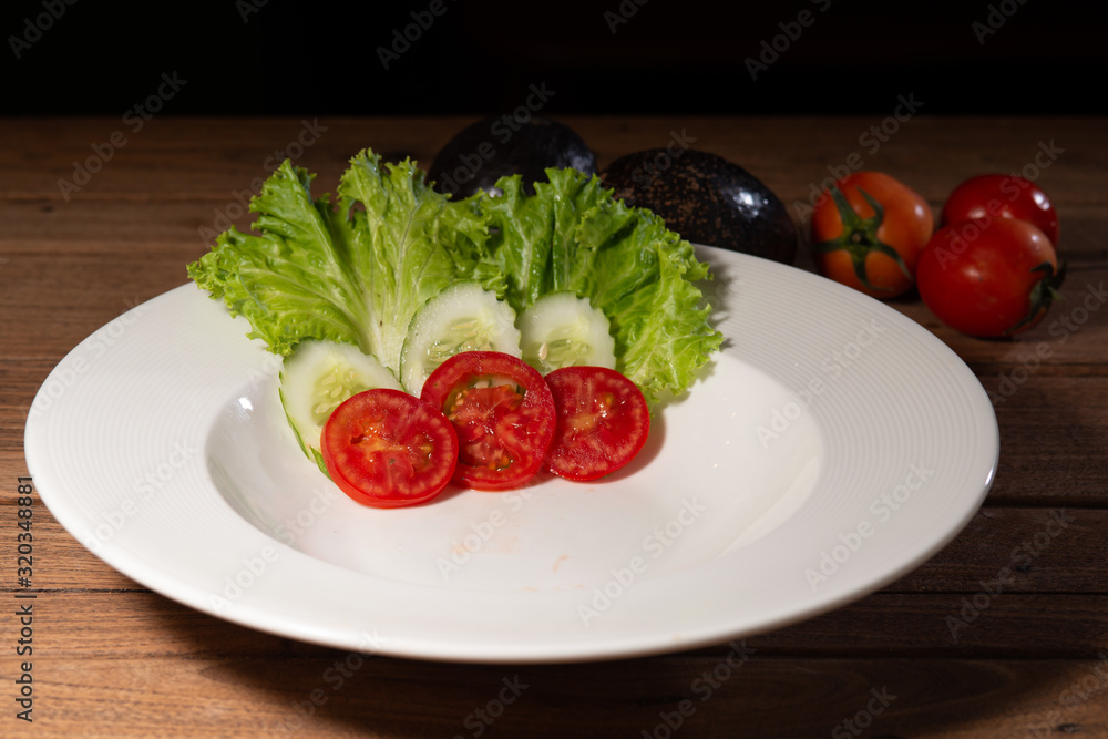 tomato slice, cucumber slice and salad in white circle dish with fresh tomato and avocado on wood table stock photo tomato slice, cucumber slice and salad in white circle dish with fresh tomato and avocado on wood table stock photo