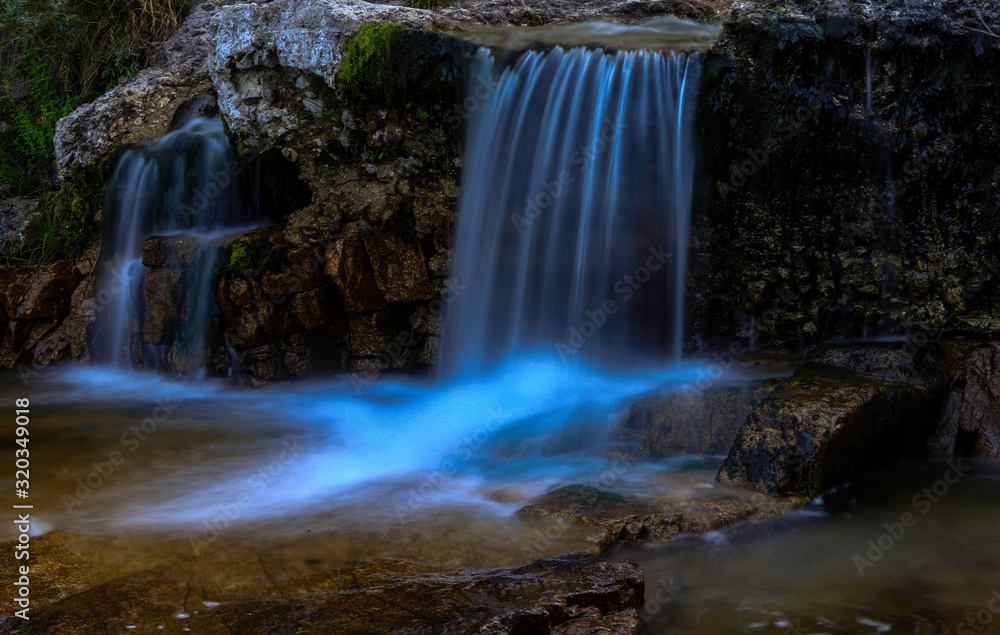 Obraz premium Cascada de un pequeño río en el anochecer con el agua suave por la alta exposición
