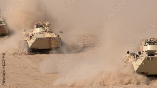 A military column of armored vehicles moves through the desert, raising dust. Special operation of the military