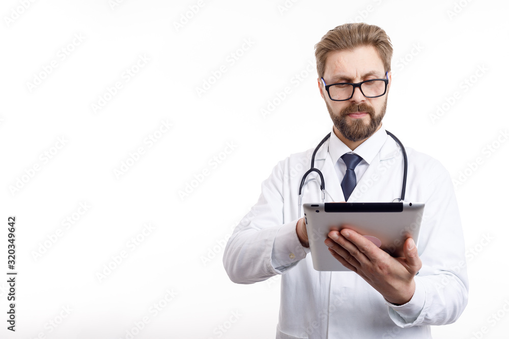 Smart brown-bearded physician in glasses using a tablet to check medical information isolated white background copyspace Smart brown-bearded physician in glasses using a tablet to check medical information isolated white background copyspace