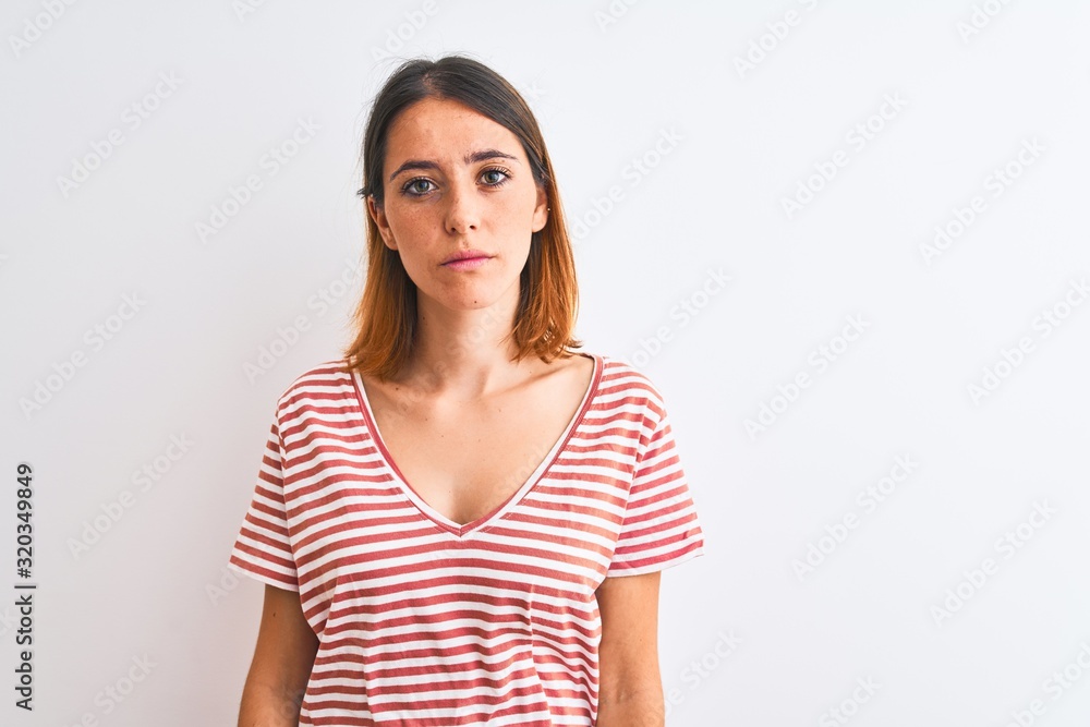 Beautiful redhead woman wearing casual striped red t-shirt over isolated background Relaxed with serious expression on face. Simple and natural looking at the camera. Beautiful redhead woman wearing casual striped red t-shirt over isolated background Relaxed with serious expression on face. Simple and natural looking at the camera.
