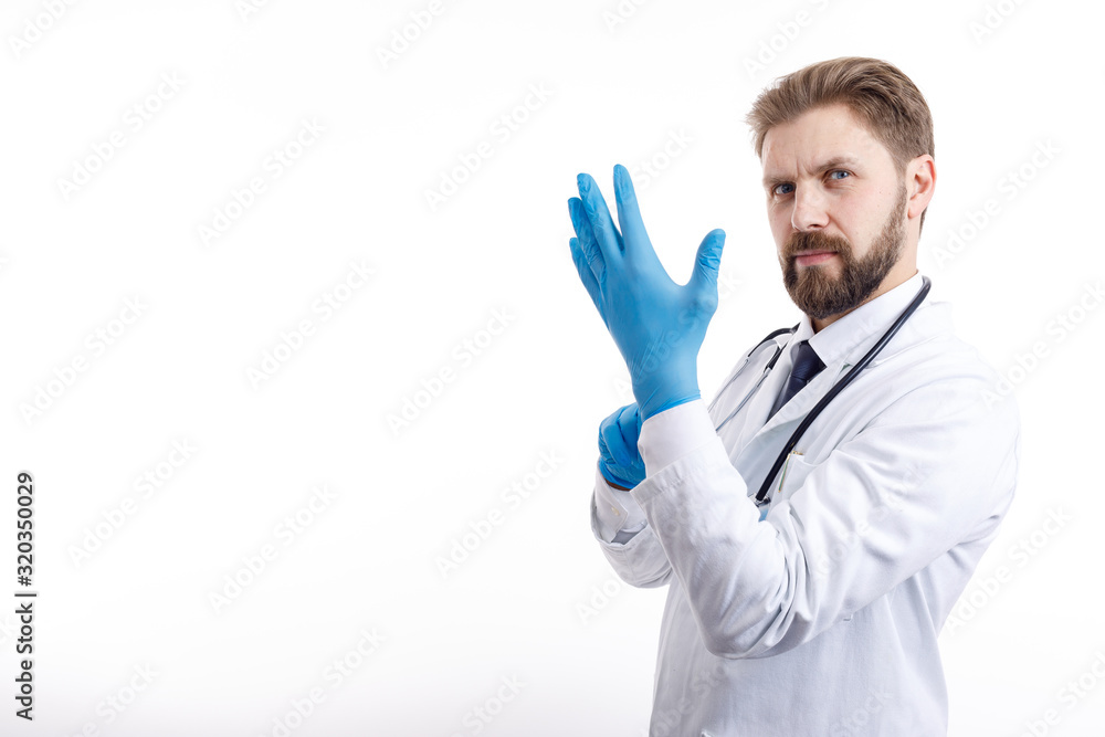 Confident bearded physician in white smock putting on blue medical gloves isolated white background copyspace Confident bearded physician in white smock putting on blue medical gloves isolated white background copyspace
